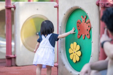 Malezya 'daki Kuala Lumpur Şehir Merkezi' ndeki KLCC Parkı 'nda 30' lu yaşlardaki babasıyla çocuk parkı ekipmanlarında oynayan bir Çinli kız..