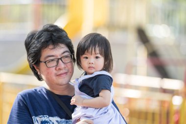 Malezya 'daki Kuala Lumpur Şehir Merkezi' ndeki KLCC Parkı 'nda 30' lu yaşlardaki babasıyla çocuk parkı ekipmanlarında oynayan bir Çinli kız..