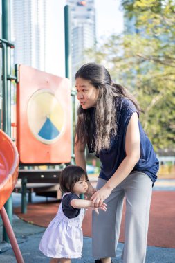 Malezya 'daki Kuala Lumpur Şehir Merkezi' ndeki KLCC Parkı 'nda 30' lu yaşlarında annesiyle birlikte çocuk parkında oynayan bir Çinli kız çocuğu..