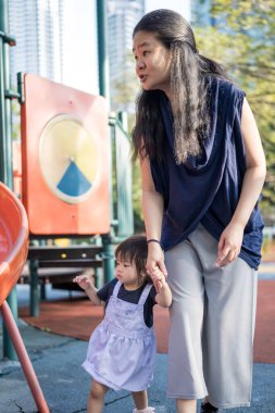 Malezya 'daki Kuala Lumpur Şehir Merkezi' ndeki KLCC Parkı 'nda 30' lu yaşlarında annesiyle birlikte çocuk parkında oynayan bir Çinli kız çocuğu..