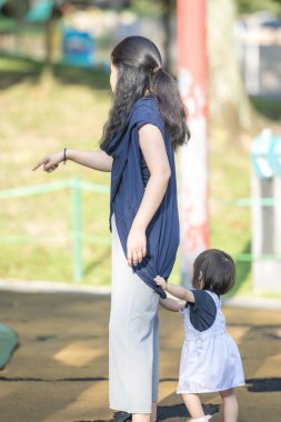 Malezya 'daki Kuala Lumpur Şehir Merkezi' ndeki KLCC Parkı 'nda 30' lu yaşlarında annesiyle birlikte çocuk parkında oynayan bir Çinli kız çocuğu..