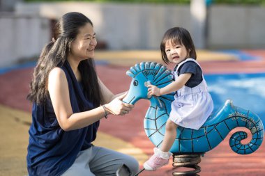 Malezya 'daki Kuala Lumpur Şehir Merkezi' ndeki KLCC Parkı 'nda 30' lu yaşlarında annesiyle birlikte çocuk parkında oynayan bir Çinli kız çocuğu..