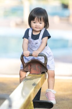 Malezya 'nın Kuala Lumpur Şehir Merkezi' ndeki KLCC Parkı 'nda sarı bir tahterevallide oynayan bir Çinli kız..