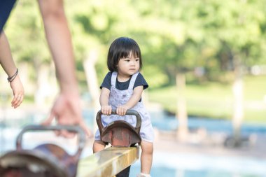 Malezya 'nın Kuala Lumpur Şehir Merkezi' ndeki KLCC Parkı 'nda otuz küsur yaşındaki annesiyle sarı bir tahterevallide oynayan bir Çinli kız..