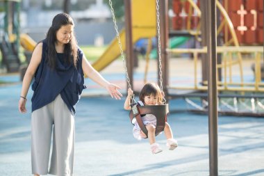 Malezya 'nın Kuala Lumpur Şehir Merkezi' ndeki KLCC Parkı 'nda otuz küsur yaşındaki annesiyle salıncakta sallanan bir Çinli kız çocuğu..