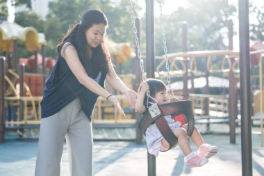 Malezya 'nın Kuala Lumpur Şehir Merkezi' ndeki KLCC Parkı 'nda otuz küsur yaşındaki annesiyle salıncakta sallanan bir Çinli kız çocuğu..