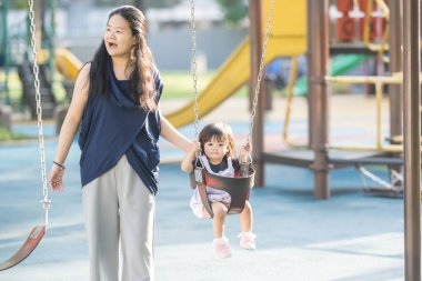 Malezya 'nın Kuala Lumpur Şehir Merkezi' ndeki KLCC Parkı 'nda otuz küsur yaşındaki annesiyle salıncakta sallanan bir Çinli kız çocuğu..