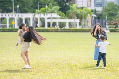 İki otuzlarında Hintli Malezyalı anne ve yedi yaşındaki oğulları ve beş yaşındaki kızları, Malezya 'nın Kuala Lumpur kentindeki Merdeka Meydanı' nda neşeyle oynuyorlar..