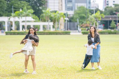 İki otuzlarında Hintli Malezyalı anne ve yedi yaşındaki oğulları ve beş yaşındaki kızları, Malezya 'nın Kuala Lumpur kentindeki Merdeka Meydanı' nda neşeyle oynuyorlar..
