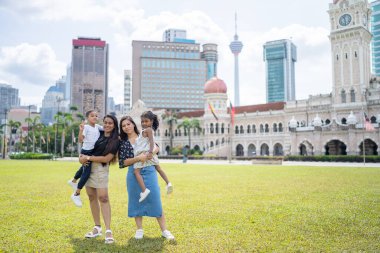İki otuzlarında Hintli Malezyalı anne ve yedi yaşındaki oğulları ve beş yaşındaki kızları, Malezya 'nın Kuala Lumpur kentindeki Merdeka Meydanı' nda neşeyle oynuyorlar..