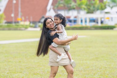 Otuz yaşlarında Hintli bir Malezyalı anne, Malezya 'nın Kuala Lumpur kentindeki Merdeka Meydanı' ndaki geniş çimlerde neşeyle oynarken, beş yaşındaki kızıyla etrafta koşuşturuyor..