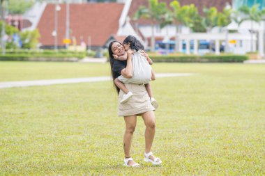 Otuz yaşlarında Hintli bir Malezyalı anne, Malezya 'nın Kuala Lumpur kentindeki Merdeka Meydanı' ndaki geniş çimlerde neşeyle oynarken, beş yaşındaki kızıyla etrafta koşuşturuyor..