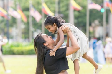 Otuz yaşlarında Hintli bir Malezyalı anne, Malezya 'nın Kuala Lumpur kentindeki Merdeka Meydanı' ndaki geniş çimlerde neşeyle oynarken, beş yaşındaki kızıyla etrafta koşuşturuyor..