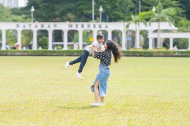 Malezya 'nın Kuala Lumpur kentindeki Merdeka Meydanı' nda, 7 yaşındaki oğlunu kucağında tutan 30 küsur Hintli Malezyalı anne neşeyle oyun oynuyor..