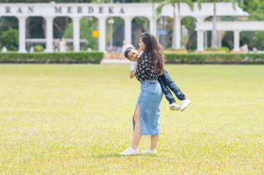 Malezya 'nın Kuala Lumpur kentindeki Merdeka Meydanı' nda, 7 yaşındaki oğlunu kucağında tutan 30 küsur Hintli Malezyalı anne neşeyle oyun oynuyor..