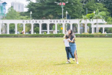 Malezya 'nın Kuala Lumpur kentindeki Merdeka Meydanı' nda, 7 yaşındaki oğlunu kucağında tutan 30 küsur Hintli Malezyalı anne neşeyle oyun oynuyor..