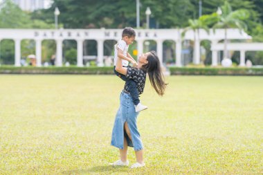 Malezya 'nın Kuala Lumpur kentindeki Merdeka Meydanı' nda, 7 yaşındaki oğlunu kucağında tutan 30 küsur Hintli Malezyalı anne neşeyle oyun oynuyor..