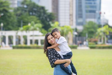 Malezya 'nın Kuala Lumpur kentindeki Merdeka Meydanı' nda, 7 yaşındaki oğlunu kucağında tutan 30 küsur Hintli Malezyalı anne neşeyle oyun oynuyor..