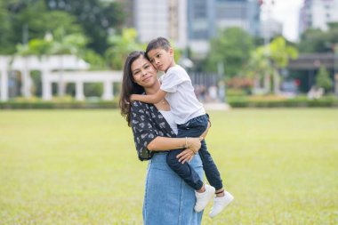 Malezya 'nın Kuala Lumpur kentindeki Merdeka Meydanı' nda, 7 yaşındaki oğlunu kucağında tutan 30 küsur Hintli Malezyalı anne neşeyle oyun oynuyor..