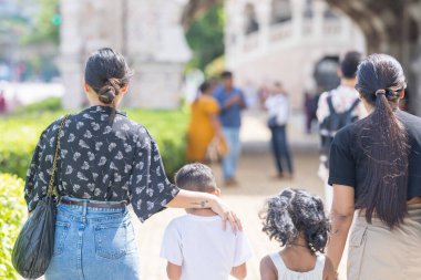 7 yaşındaki oğulları ve 5 yaşındaki kızlarıyla birlikte Kuala Lumpur, Malezya 'daki batı tarzı tarihi bir binanın önünde mutlu mesut yürüyen 30 küsur Hintli anne..