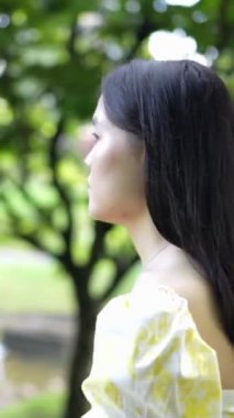 Malezya 'nın Kuala Lumpur yakınlarındaki Bukit Jalil' de keman çantasıyla dolaşan 20 'li yaşlarda, sarı elbiseli bir Çinli kadın. (dikey video)