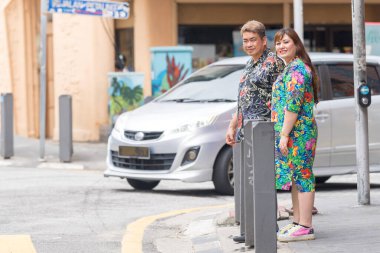 50 'li yaşlarda Malaylı bir adam ve 30' lu yaşlarda renkli elbiseli Çinli bir çift Çin Mahallesi Kuala Lumpur, Malezya 'da yaya geçidinde yürüyorlar..