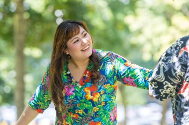 50 'li yaşlarında Malezyalı bir adam renkli gömlek giyiyor ve 30' lu yaşlarında Çinli bir kadın Malezya, Kuala Lumpur 'daki KLCC Parkı' nda ağaçların gölgesinde kovalamaca oynuyor..