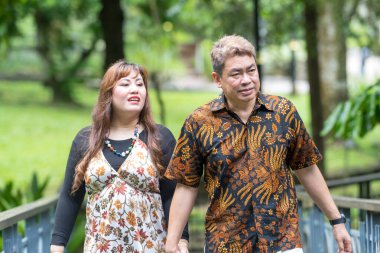 50 'li yaşlarında Malezyalı bir adam geleneksel 30' lu yaşlarda geleneksel elbiseler giyen Çinli bir kadın, Kuala Lumpur 'daki Botani Perdana Köprüsü' nde birlikte vakit geçiriyorlar.