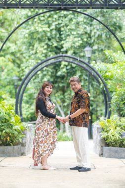 50 'li yaşlarında Malezyalı bir adam geleneksel 30' lu yaşlarda geleneksel bir elbise giyen Çinli bir kadın Malezya 'nın başkenti Kuala Lumpur' da Taman Botani Perdana 'da bir anma fotoğrafına poz veriyor..