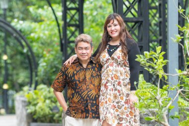 50 'li yaşlarında Malezyalı bir adam geleneksel 30' lu yaşlarda geleneksel bir elbise giyen Çinli bir kadın Malezya 'nın başkenti Kuala Lumpur' da Taman Botani Perdana 'da bir anma fotoğrafına poz veriyor..