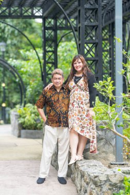 50 'li yaşlarında Malezyalı bir adam geleneksel 30' lu yaşlarda geleneksel bir elbise giyen Çinli bir kadın Malezya 'nın başkenti Kuala Lumpur' da Taman Botani Perdana 'da bir anma fotoğrafına poz veriyor..