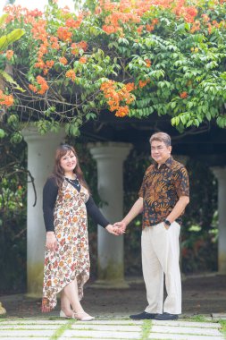 50 'li yaşlarında Malezyalı bir adam geleneksel 30' lu yaşlarda geleneksel bir elbise giyen Çinli bir kadın Malezya 'nın başkenti Kuala Lumpur' da Taman Botani Perdana 'da bir anma fotoğrafına poz veriyor..