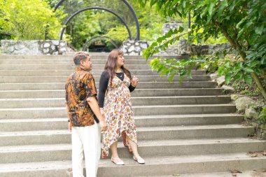 50 'li yaşlarında Malezyalı bir adam geleneksel 30' lu yaşlarda geleneksel elbiseler giyen Çinli bir kadın, Malezya 'nın Kuala Lumpur kentindeki Taman Botani Perdana' da merdivenlerde birlikte vakit geçiriyorlar..