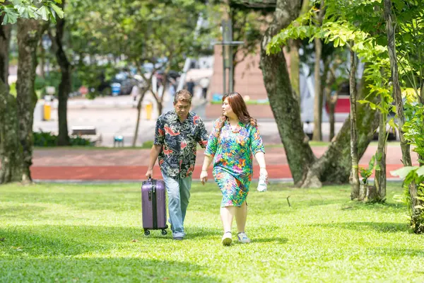 50 'li yaşlarda Malezyalı bir adam renkli gömlek giyiyor ve 30' lu yaşlarında Çinli bir kadın Malezya 'nın Kuala Lumpur kentindeki KLCC Parkı' nda birlikte yürüyor..