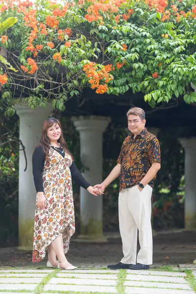 50 'li yaşlarında Malezyalı bir adam geleneksel 30' lu yaşlarda geleneksel bir elbise giyen Çinli bir kadın Malezya 'nın başkenti Kuala Lumpur' da Taman Botani Perdana 'da bir anma fotoğrafına poz veriyor..