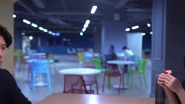 Tayvanlı erkek ve kadın 73 'lerinde ve Güney Asyalı bir kadın Daan Bölgesi, Tayvan' da bir üniversite kafeteryasında dostça sohbet ediyorlar. Yavaş çekim