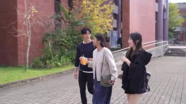 Tayvanlı erkek ve kadın 20 'li yaşlarda ve Güney Asyalı bir kadın birlikte yürüyorlar ve Tayvan, Daan Bölgesi' nde bir üniversite kampüsünde arkadaşça sohbet ediyorlar. Yavaş çekim