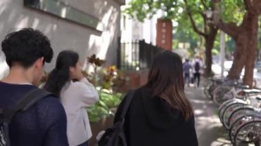 Tayvanlı erkek ve kadın 20 'li yaşlarda ve Güney Asyalı bir kadın birlikte yürüyorlar ve Tayvan, Daan Bölgesi' nde bir üniversite kampüsünde arkadaşça sohbet ediyorlar. Yavaş çekim
