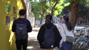 Tayvanlı erkek ve kadın 20 'li yaşlarda ve Güney Asyalı bir kadın birlikte yürüyorlar ve Tayvan' ın Taipei şehrindeki Daan Bölgesi 'nde bir üniversite yakınlarında arkadaşça sohbet ediyorlar. Yavaş çekim