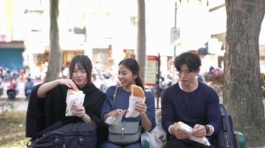 Taipei 'nin Da' an bölgesinde, 20 'li yaşlarda bir grup öğrenciyi, Tayvanlı erkekleri, kadınları ve Güney Asyalı bir kadını, bir sokak bankında oturup waffle yerken gösteren yavaş çekim bir video var..