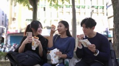 Taipei 'nin Da' an bölgesinde, 20 'li yaşlarda bir grup öğrenciyi, Tayvanlı erkekleri, kadınları ve Güney Asyalı bir kadını, bir sokak bankında oturup waffle yerken gösteren yavaş çekim bir video var..