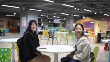 Yavaş çekimde, Taipei 'nin Da' an Bölgesi 'ndeki bir üniversite kafeteryasında otururken, biri Tayvanlı, biri Güney Asyalı iki genç kadını dostça sohbet ederken görüntülüyor..