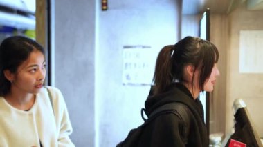 Bir Tayvanlı ve bir Güney Asyalı iki genç kadının, Taipei 'nin Da' an Bölgesi 'ndeki bir üniversitenin yakınındaki gözleme dükkanında sohbet edip waffle siparişi verdiklerini gösteren yavaş çekim bir video..