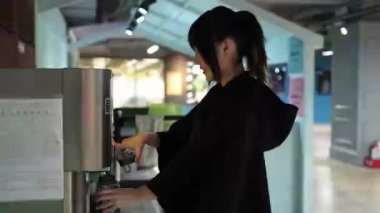 20 'li yaşlarında genç bir Tayvanlı kadının sunucudan su doldurduğu ve Taipei' nin Da 'an Bölgesi' ndeki bir üniversite kafeteryasında içki içtiği yavaş çekim videosu..