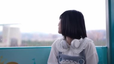 Tayvanlı genç bir kadın yirmili yaşlarda dönme dolaba biniyor, fotoğraf çekiyor ve Taipei 'nin Shilin ilçesindeki bir lunaparkta kulaklıkla müzik dinliyor..
