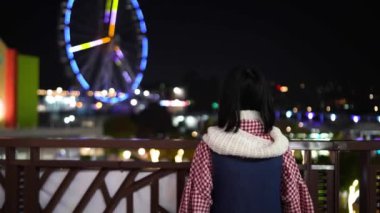 Tayvan 'ın Shilin Bölgesi' nde yirmili yaşlardaki Tayvanlı bir kadın Tayvan 'daki bir lunaparkta gece vakti güzel aydınlatılmış dönme dolaba bakıyor..