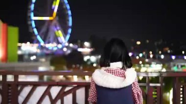 Tayvan 'ın Shilin Bölgesi' nde yirmili yaşlardaki Tayvanlı bir kadın Tayvan 'daki bir lunaparkta gece vakti güzel aydınlatılmış dönme dolaba bakıyor..