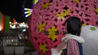 Tayvan 'ın Shilin Bölgesi' nde yirmili yaşlardaki Tayvanlı bir kadın Tayvan 'daki bir lunaparkta gece vakti güzel aydınlatılmış dönme dolaba bakıyor..