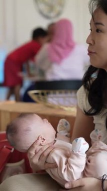 Haziran 'da Selangor Malezya' da 20 'li yaşlarda Çinli bir kadın batı tarzı şık bir kafede birkaç aylık bir bebeği sakinleştiriyor.