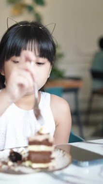 Haziran ayında Malezya 'nın Selangor kentindeki şık Batı tarzı kafede çikolatalı pasta yiyen altı yaşındaki Çinli kız, dikey yavaş çekim videosunda.